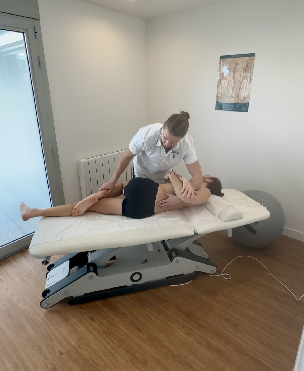 Séance d'ostéopathie au cabinet de Clamart : technique sur le bassin, patient allongé sur la table de consultation